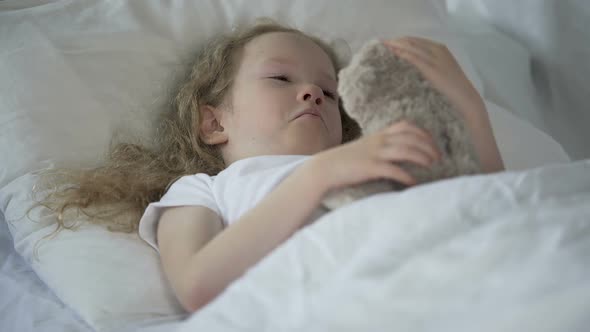 Lonely Young Girl Lying in Bed and Hugging Toy, Unhappy Child Missing Parents alt