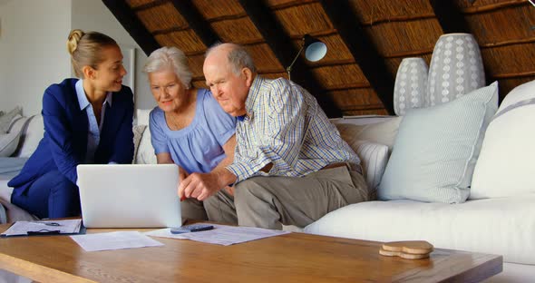 Senior couple with real estate agent discussing over laptop at home 4k alt