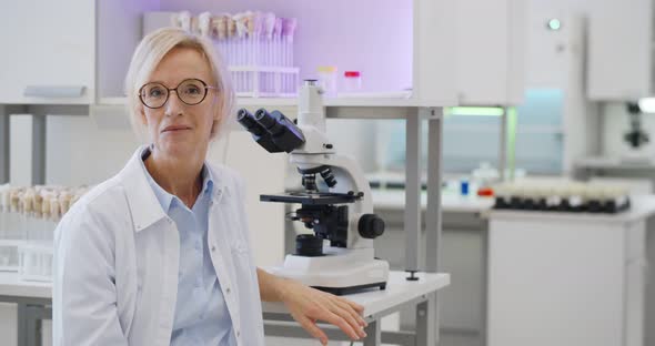 Mature Female Scientist Using Microscope Studying Samples in Biotechnology Lab alt