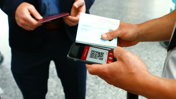 Airport male staff using mobile phone to scan the passport alt