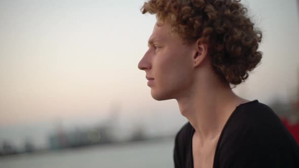 White Male with Red Curly Hair Looking at the Sea Black Shirt alt