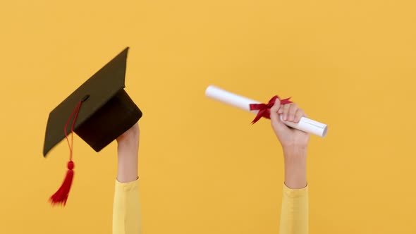 Hands holding square academic cap and degree paper roll celebrating graduation