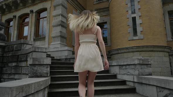 Blonde in Dress Runs Up the Stairs To the Building