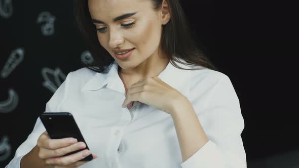 Charming Woman Smiling and Using Her Phone with Camera Movement alt