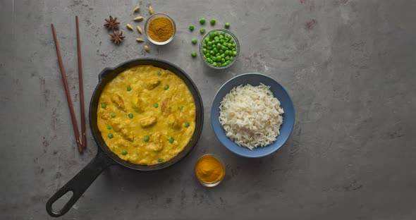 Bubbling hot tasty butter chicken curry dish with rice in a cast iron pan