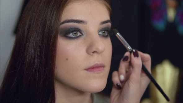 Makeup Artist Applying Eye Shadow Makeup to Model's Eye alt