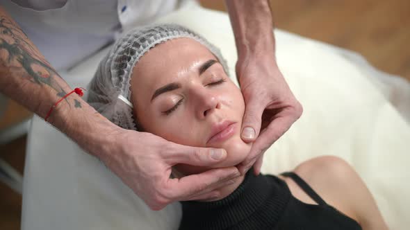 High Angle View Young Slim Beautiful Woman in Hair Cap Lying in Beauty Salon with Male Hands alt