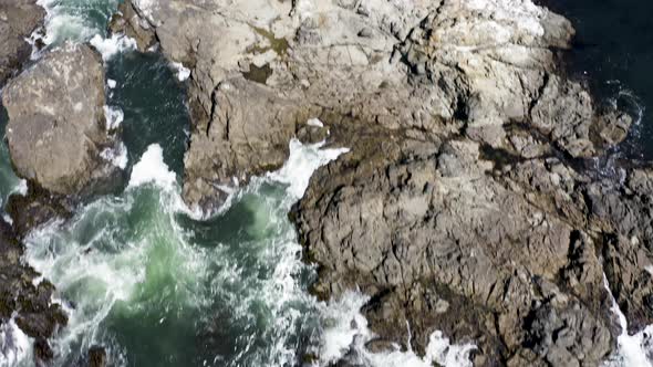 Aerial push-in and tilt-up over crashing waves on the rocky Sea Ranch, California coast alt