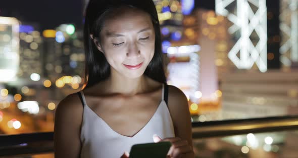 Woman looking at mobile phone with the background of cityscape in Hong Kong  alt