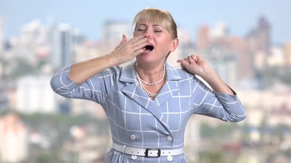Middle-aged Woman Is Yawning on Blurred Background alt
