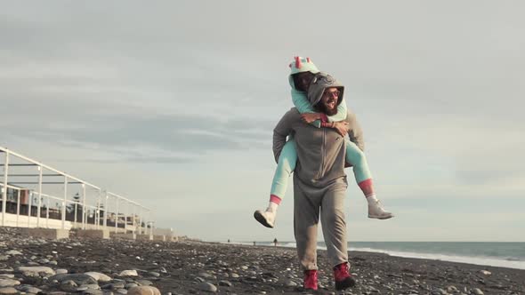Man Carries His Woman on His Back on the Beach alt