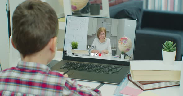 Screen Shows Online Lecture with Teacher Explaining Subject From a Classroom Boy Writes Down alt