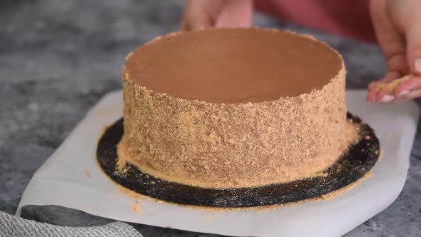 Female Hands Use the Crumbs to Decorate the Sides of the Cake