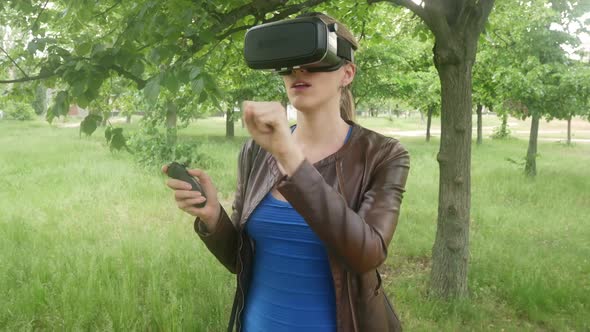 Young Woman In A Virtual Reality Helmet Uses A Virtual App In The Park