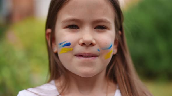 Headshot of Patriotic Charming Ukrainian Girl with Face Painting Looking at Camera and Looking Away alt