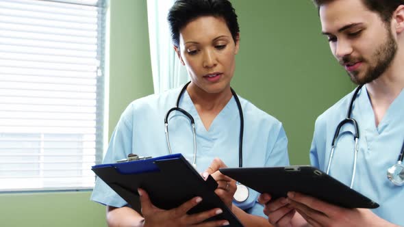 Two doctors discussing over digital tablet alt