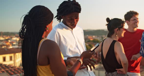 Young woman holding smartphone and talking with young man alt