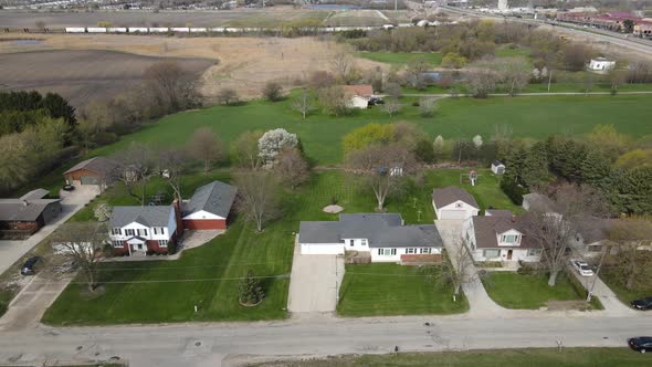 Aerial view of rural farm land and homes with water and train tracks in the distance.