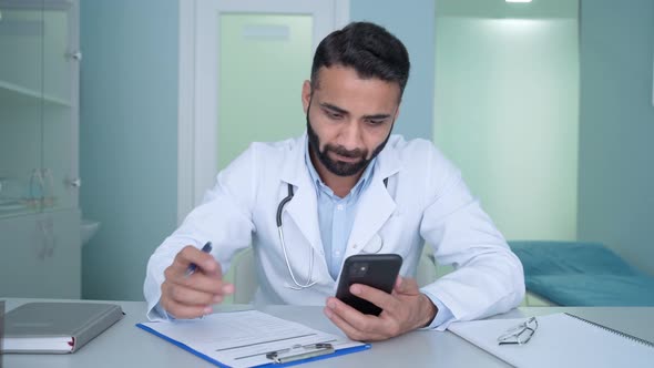 Indian Male Doctor in Hospital Clinic Uses Cell Mobile Phone Apps Texting alt