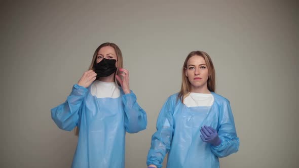 Two Young Girls Doctors Remove Special Protective Clothes and Rejoice Isolated on White Background