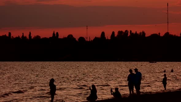 Silhouette of people walking along the sea coast at a beautiful sunset.