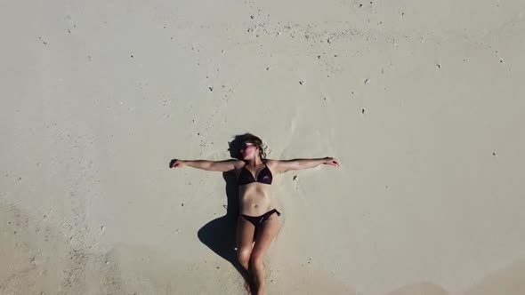 Aerial View of a Beach Surrounded By Waves with a Woman Sunbathing Lying on a Sand