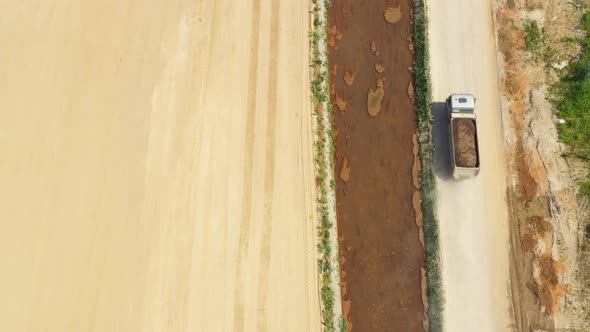 Dumper truck with sand is going, passing over highway construction side. Aerial View alt