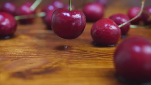 Ripe Red Cherries Falls on Wooden Table with Water Drops