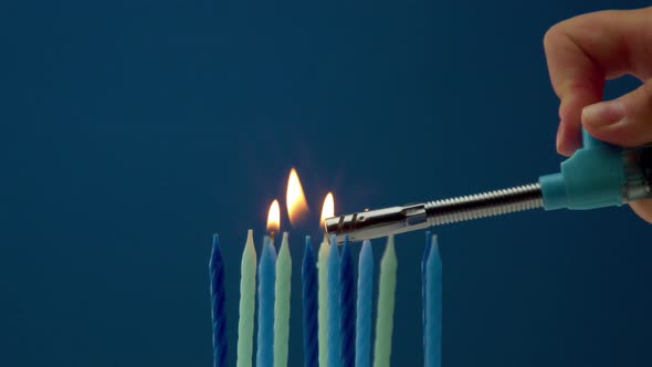 Some Cold Tones Candles on Blue Background and Someone Lighting Candles