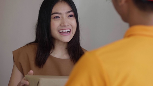 Young delivery Asian man holding a cardboard box.