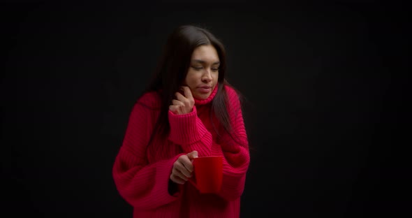 Brunette in a Pink Sweater is Frozen and Warms Up with a Hot Drink in a Red Mug