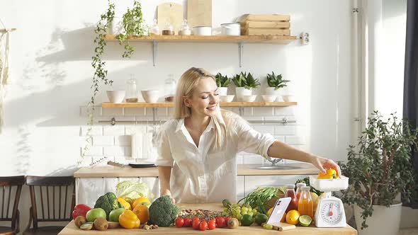 An Attractive Woman Stands at a Table with a Large Amount of Fresh Vegetables and Fruits She Follows