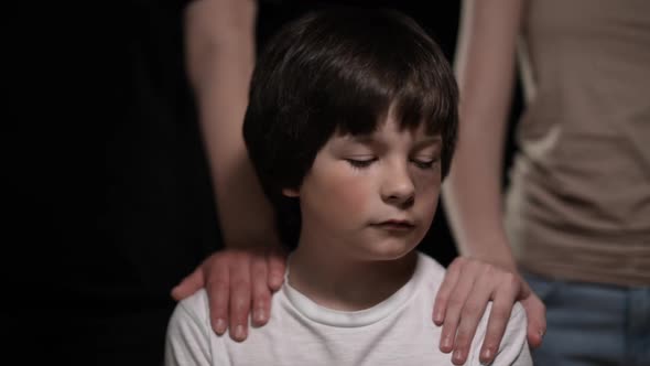 Portrait of Sad Bruised Caucasian Beaten Boy Looking at Camera As Female Hands Touching Shoulders alt