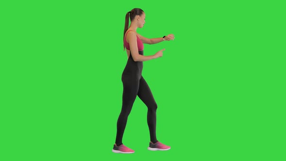 Running Woman Jogger Using Smart Watch While Walking on a Green Screen Chroma Key