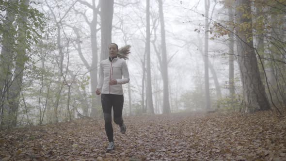 Slow Motion Woman Jogging on Foggy Day in Autumn Forest Front View