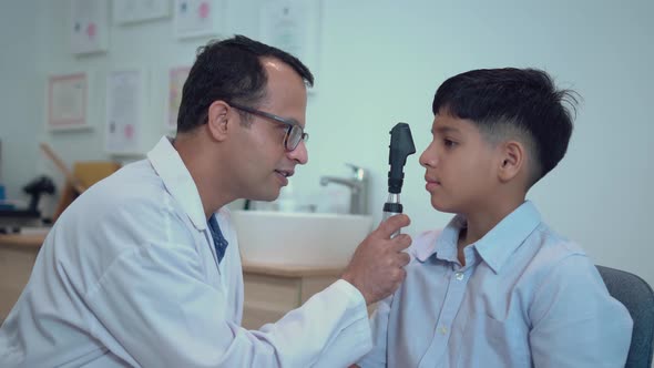 Boy doing eye test checking examination with optometrist in optical shop