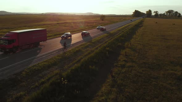 Aerial shot: single man riding bicycle by roadside.