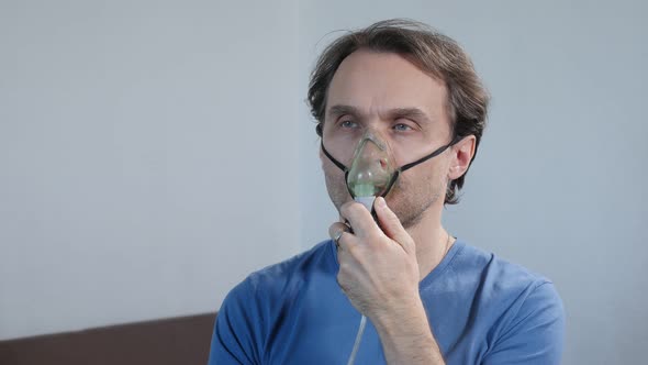Adult Man Breathing Through Nebulizer During Inhalation Therapy Procedure