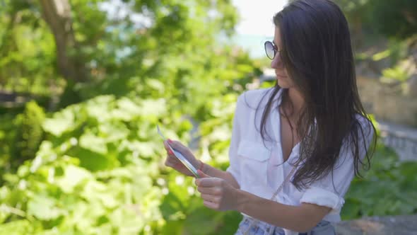 Pretty Tourist Girl with White Shirt and Sunglasses Holding Tourist Map and Checking the Way alt