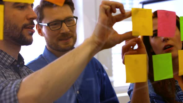 Business executives discussing over sticky notes alt