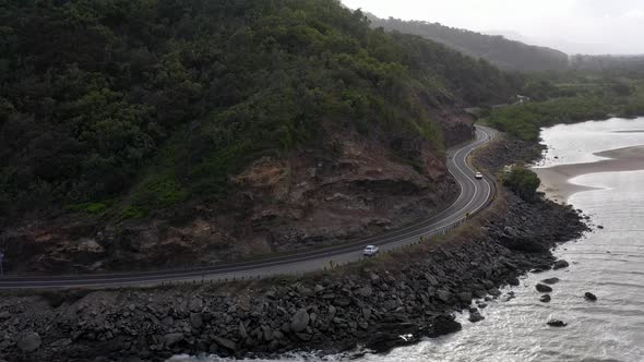 Captain Cook Highway aerial with white car and rocky coast, Far North Queensland, Australia alt