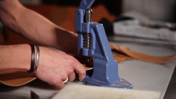 Craftsman Is Using Hand Press for Installing Metal Fittings on a Leather Good alt