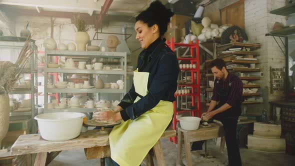 Woman and Man Work On Wheels In Pottery Studio