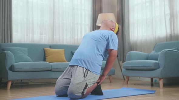 Fat Asian Man Doing Yoga In Camel Pose On Mat  At Home alt