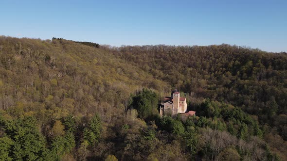 Aerial view of shrine built into side of mountain with trees all around on a clear blue day.