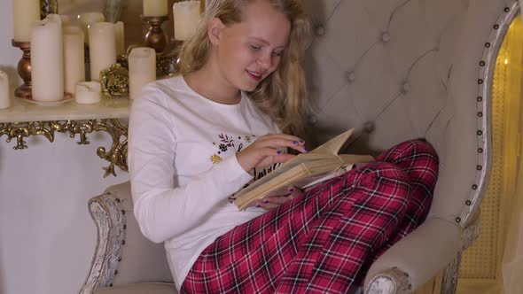 Girl Reading Book Sitting in Armchair alt