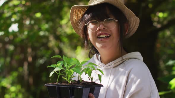 Portrait of asian girl gardening and smiling on sunny day alt