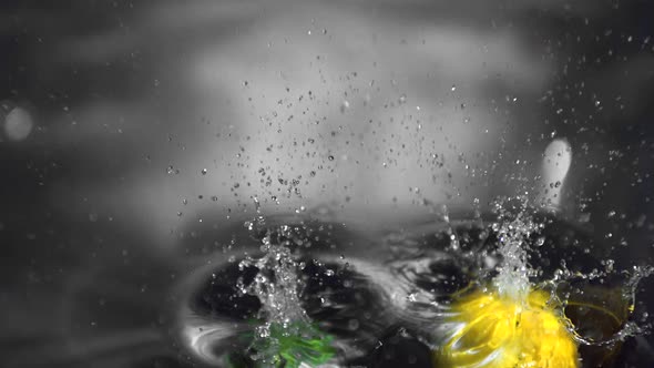Lemon and lime falling into water close up
