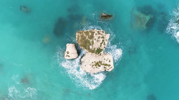 Aerial Top View of Waves Break on Rocks in a Blue Ocean alt