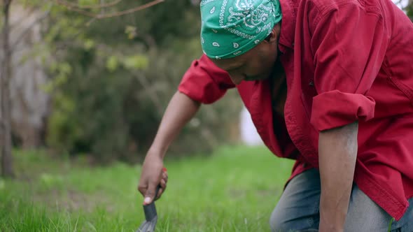 Young Concentrated Man Using Gardening Fork at Backyard on Summer Day alt